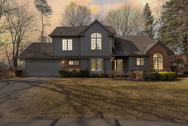 view of front facade with a garage, a lawn, board and batten siding, and driveway