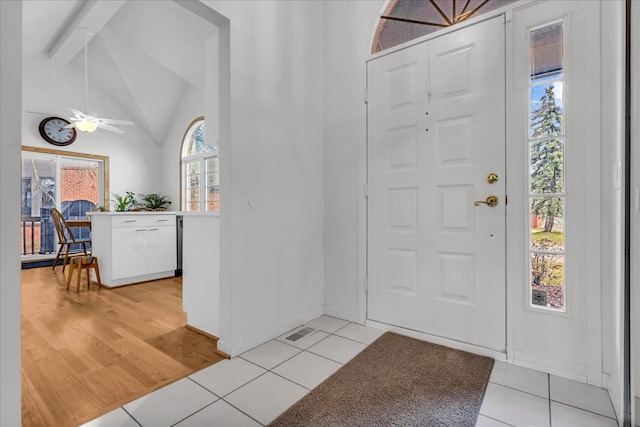 foyer featuring vaulted ceiling, light tile patterned flooring, visible vents, and ceiling fan