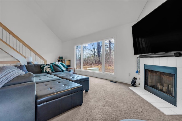 living room featuring visible vents, baseboards, stairs, carpet floors, and a tile fireplace
