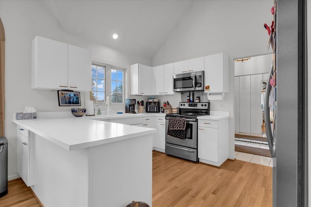 kitchen with a peninsula, stainless steel appliances, light wood-style floors, and a sink