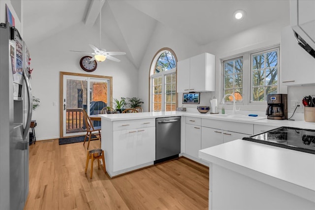 kitchen with light wood-style flooring, appliances with stainless steel finishes, a peninsula, and white cabinets