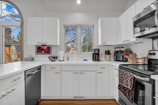 kitchen with visible vents, a sink, stainless steel appliances, light countertops, and white cabinets