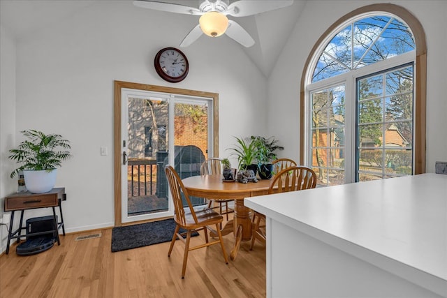 dining area featuring visible vents, baseboards, vaulted ceiling, light wood-style flooring, and a ceiling fan