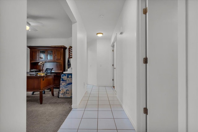 corridor featuring light tile patterned floors, light colored carpet, and baseboards