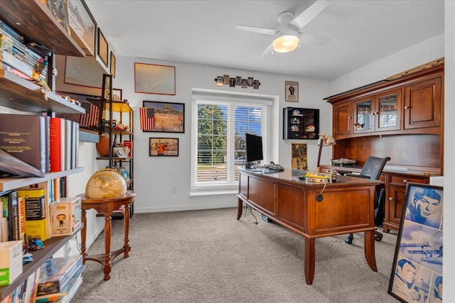 office featuring a ceiling fan, light colored carpet, and baseboards