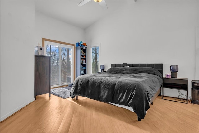 bedroom with access to exterior, high vaulted ceiling, baseboards, and wood finished floors