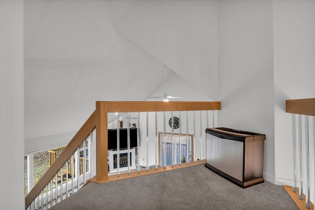 unfurnished living room featuring a ceiling fan, a high ceiling, and carpet