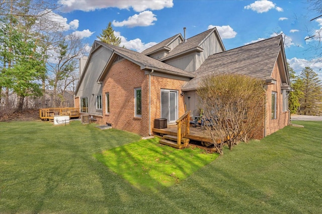 rear view of house with a wooden deck, brick siding, roof with shingles, and a lawn