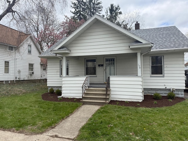 bungalow featuring a chimney, a front lawn, a porch, and a shingled roof