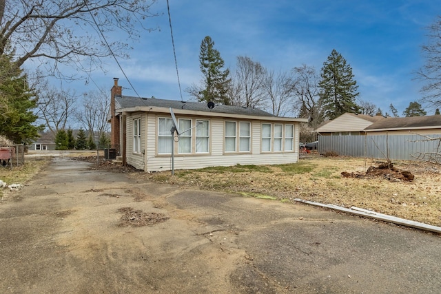 2174 Middlebelt Rd, West Bloomfield, MI 48324 - back of house with a chimney, driveway, and fence