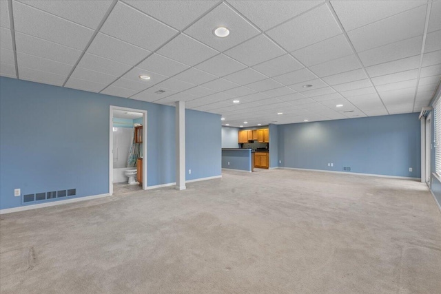 unfurnished living room with baseboards, visible vents, recessed lighting, a drop ceiling, and light carpet