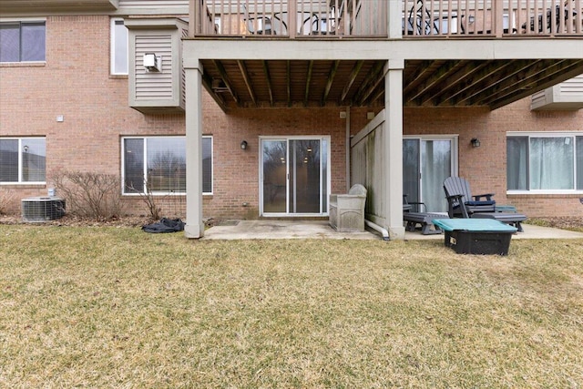 rear view of house featuring a patio, brick siding, central AC, and a lawn
