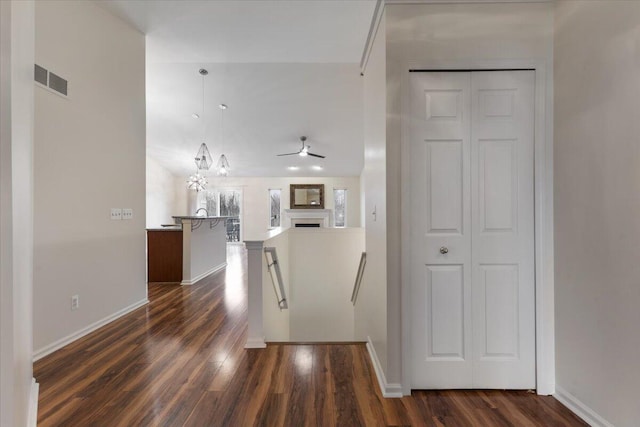 hallway featuring baseboards, an upstairs landing, visible vents, and dark wood-style flooring