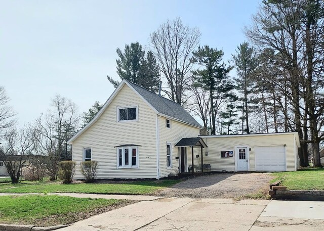 view of side of home featuring a yard, an attached garage, and gravel driveway