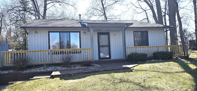 view of front of property with a front yard and a shingled roof