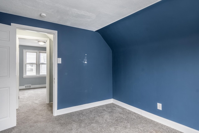 additional living space with baseboards, a textured ceiling, carpet floors, visible vents, and lofted ceiling
