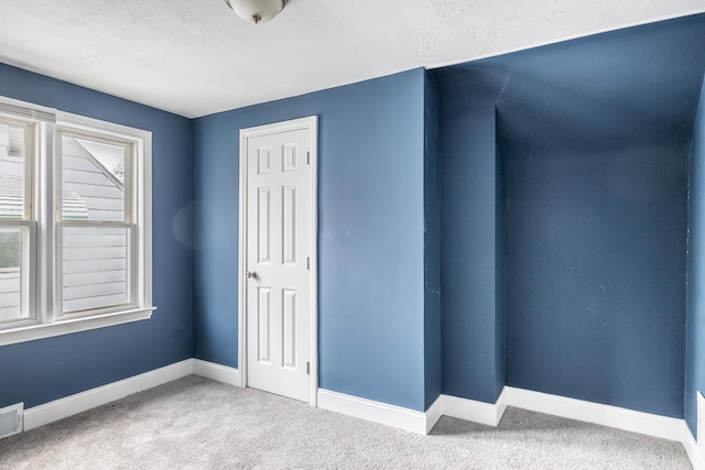 unfurnished room featuring a textured ceiling, carpet flooring, baseboards, and visible vents