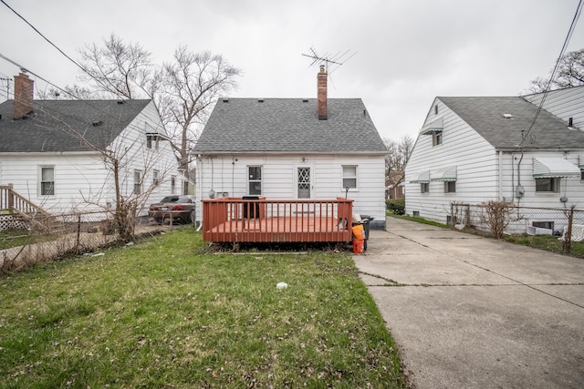 rear view of property with roof with shingles, fence, a lawn, and a chimney