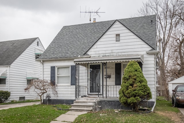 bungalow-style home with a front yard and roof with shingles