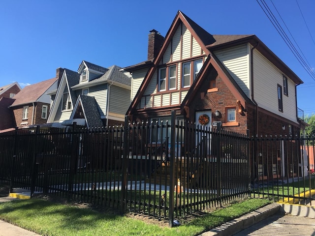 tudor-style house featuring brick siding, stone siding, and a fenced front yard
