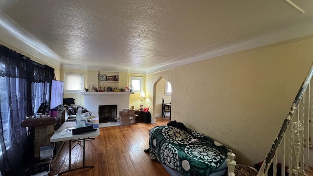 living room with a textured wall, arched walkways, a textured ceiling, and hardwood / wood-style flooring