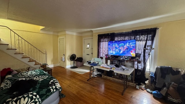 living area with stairway, wood finished floors, baseboards, and a textured ceiling