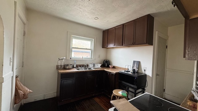 kitchen with dark brown cabinets, light countertops, dark wood-style flooring, a textured ceiling, and a sink