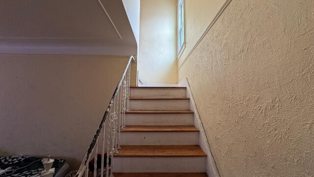 stairway featuring a textured wall