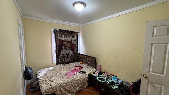 bedroom with wood finished floors and ornamental molding
