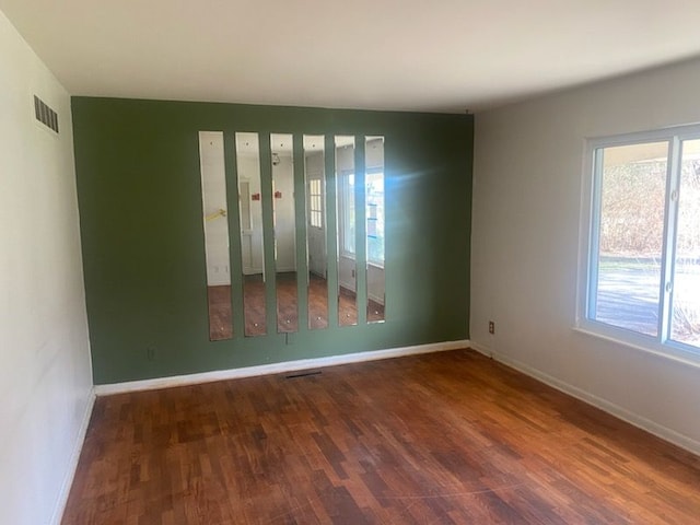 6111 Woodmoor Dr, Burton, MI 48509 - empty room with baseboards, visible vents, wood finished floors, and a healthy amount of sunlight
