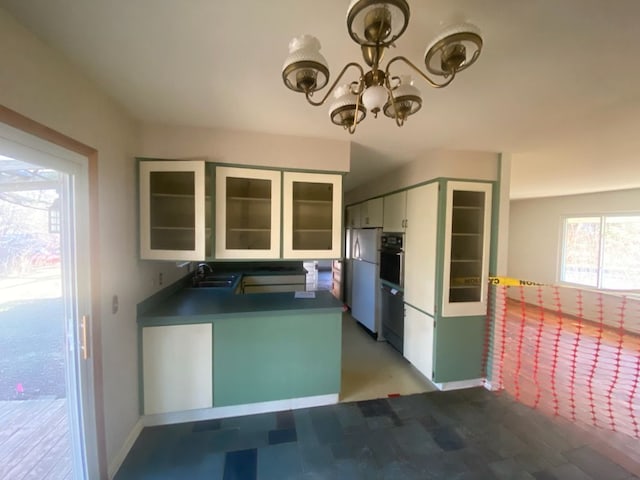 6111 Woodmoor Dr, Burton, MI 48509 - kitchen featuring a sink, freestanding refrigerator, oven, white cabinets, and an inviting chandelier