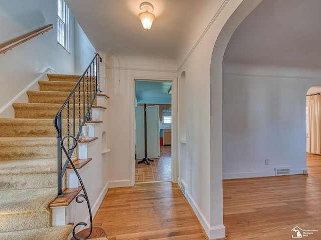 foyer entrance featuring stairway, wood finished floors, visible vents, arched walkways, and baseboards