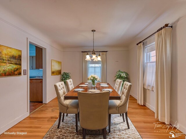 dining area with baseboards, an inviting chandelier, and light wood-style floors