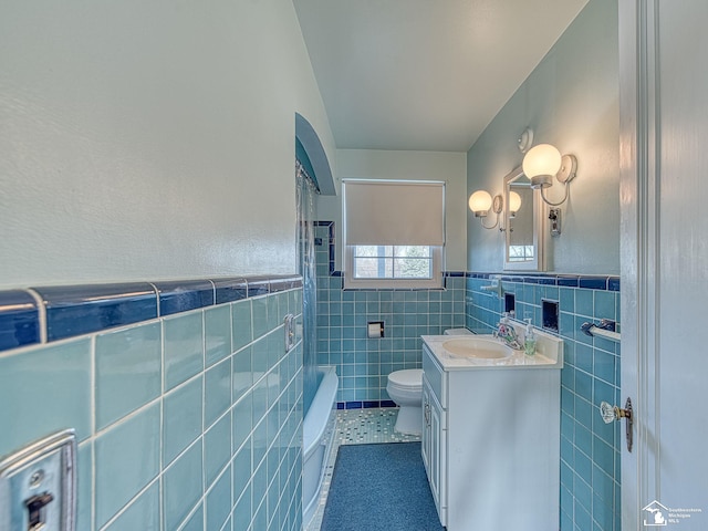 full bath with a wainscoted wall, tile patterned floors, toilet, vanity, and tile walls