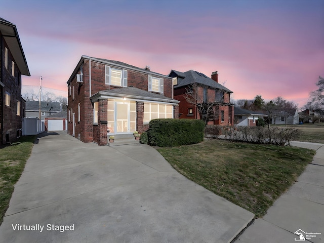 traditional-style house featuring an outdoor structure, brick siding, a yard, and driveway