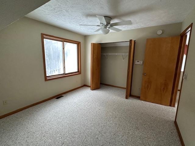 unfurnished bedroom with baseboards, a textured ceiling, visible vents, light carpet, and a closet
