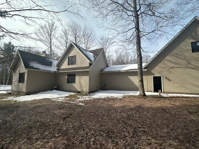 snow covered rear of property with a chimney and a patio area