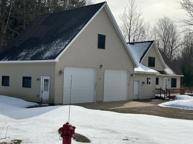 snow covered property with driveway and an attached garage