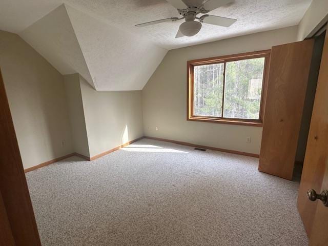 bonus room featuring baseboards, carpet, and a textured ceiling