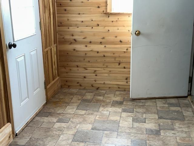 unfurnished room with stone finish floor and wood walls