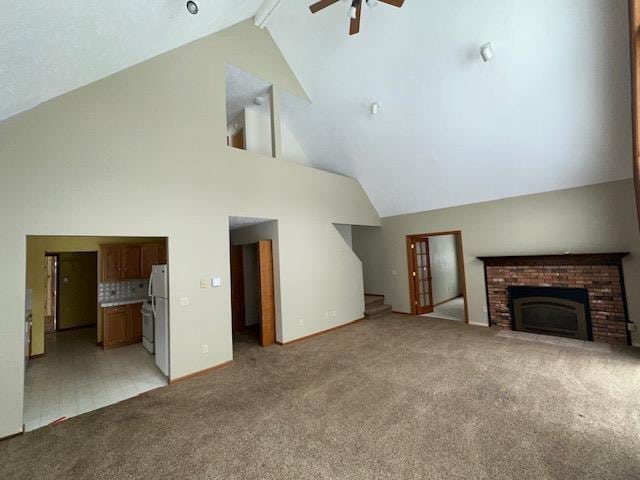 unfurnished living room with a brick fireplace, beamed ceiling, stairway, a ceiling fan, and light carpet