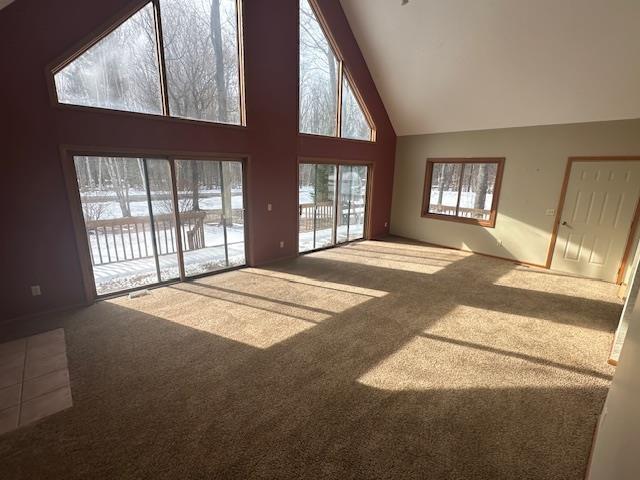 unfurnished living room featuring carpet floors and high vaulted ceiling