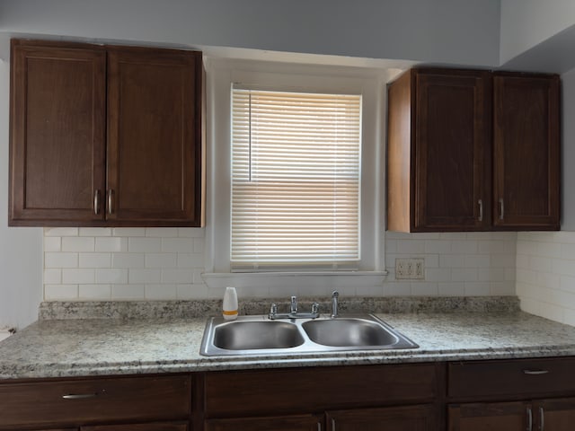 kitchen featuring light countertops, a sink, dark brown cabinets, and decorative backsplash