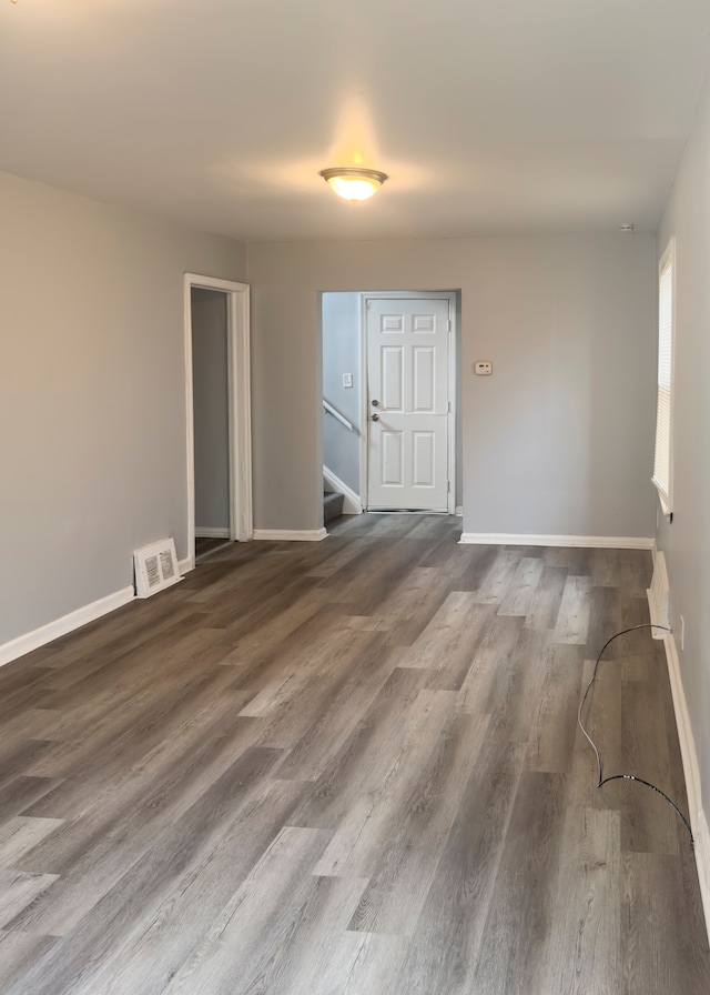 empty room with baseboards, visible vents, wood finished floors, and stairway