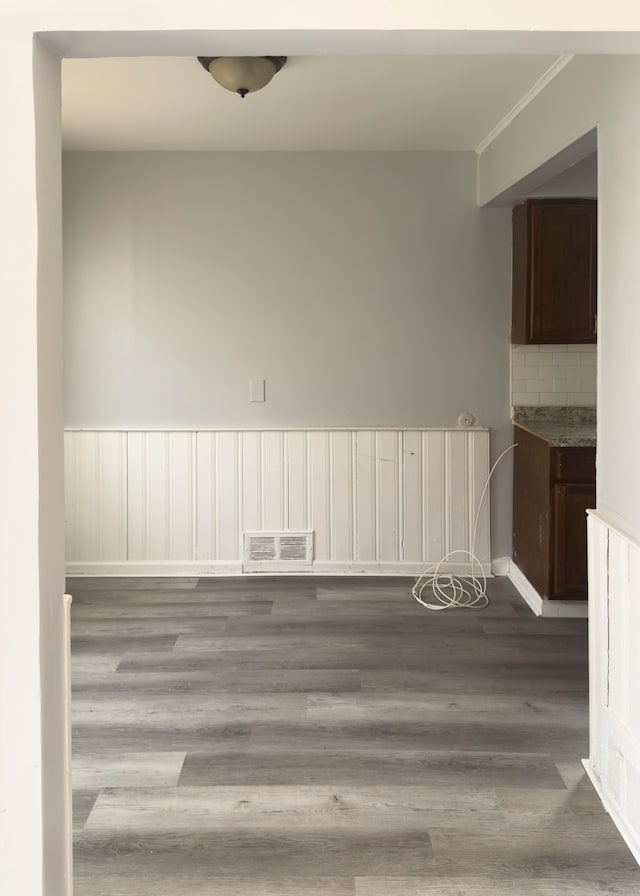 spare room featuring baseboards, ornamental molding, visible vents, and wood finished floors