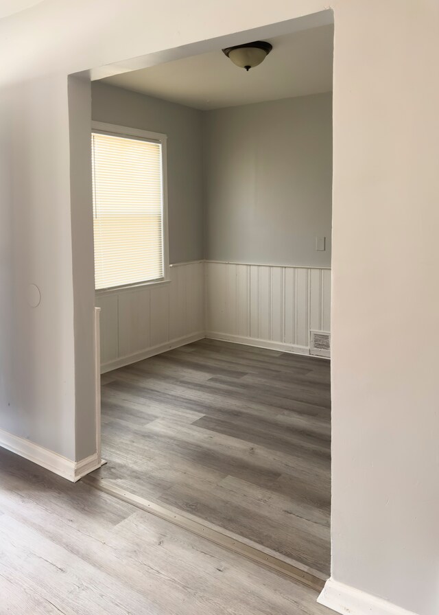 spare room with wainscoting, visible vents, and wood finished floors