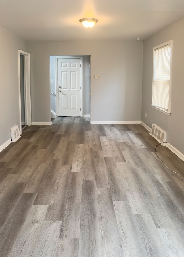 empty room featuring baseboards, visible vents, and dark wood-type flooring