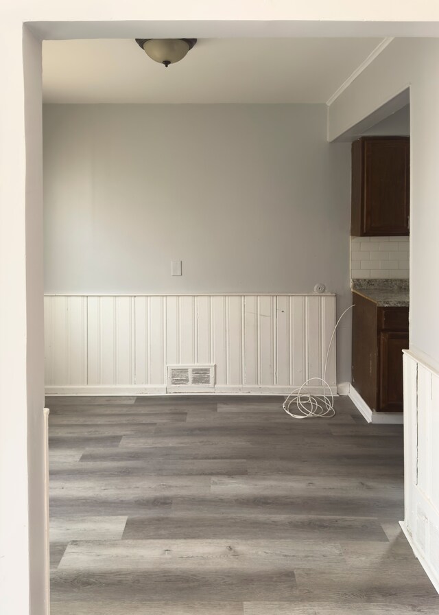 empty room featuring baseboards, visible vents, crown molding, and wood finished floors