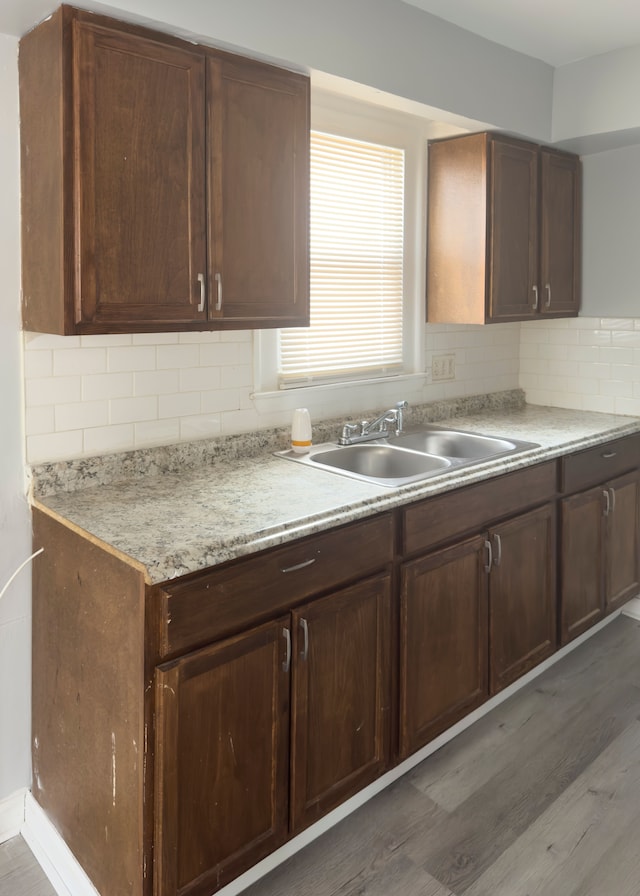kitchen with light countertops, wood finished floors, a sink, and decorative backsplash