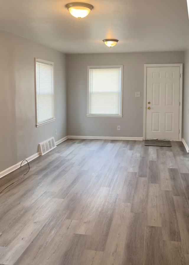 spare room with baseboards, visible vents, wood finished floors, and a healthy amount of sunlight
